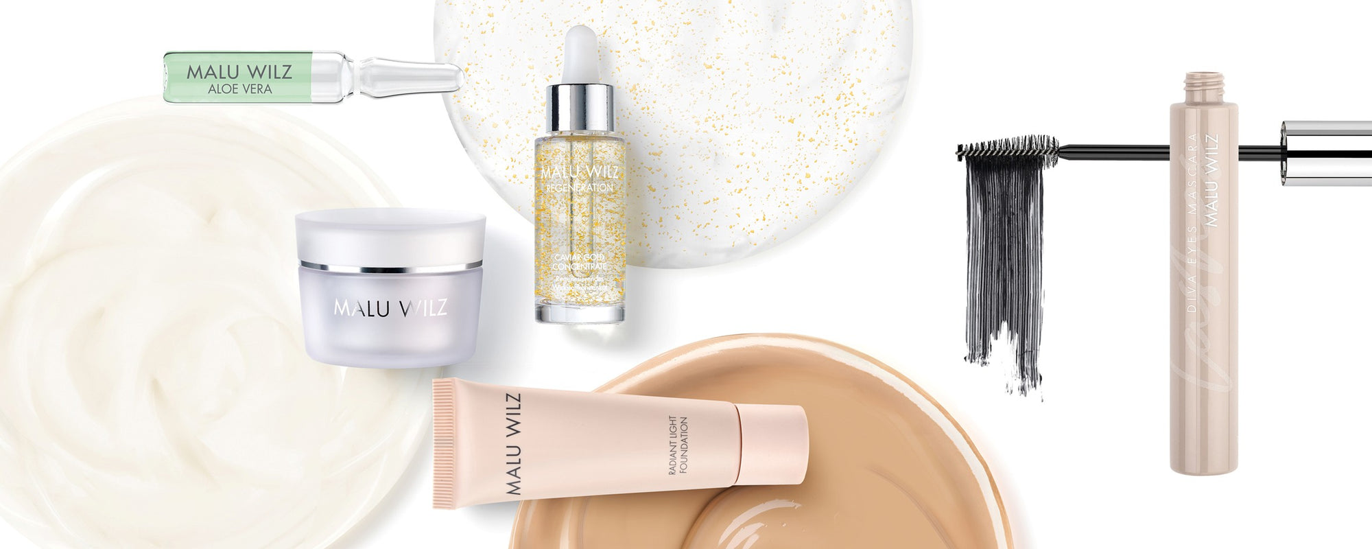 MALU WILZ Kosmetikprodukte: Auswahl aus Pflege und Make-up wie Foundation, Mascara, Serum und Gesichtscreme vor cremigen Texturen.