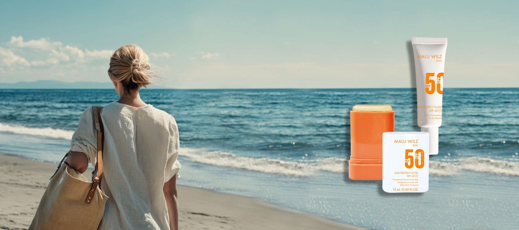 Frau am Strand mit großer Tasche über der Schulter, Rückansicht, Meer und blauer Himmel, Sun Care Produkte an der Seite