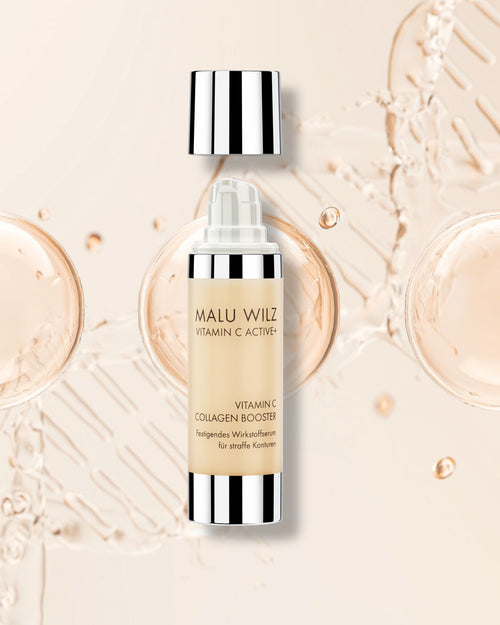 Malu Wilz Vitamin C Collagen Booster in einem beigefarbenen Spender mit silbernen Akzenten vor einem Hintergrund aus goldenen Flüssigkeitstropfen.